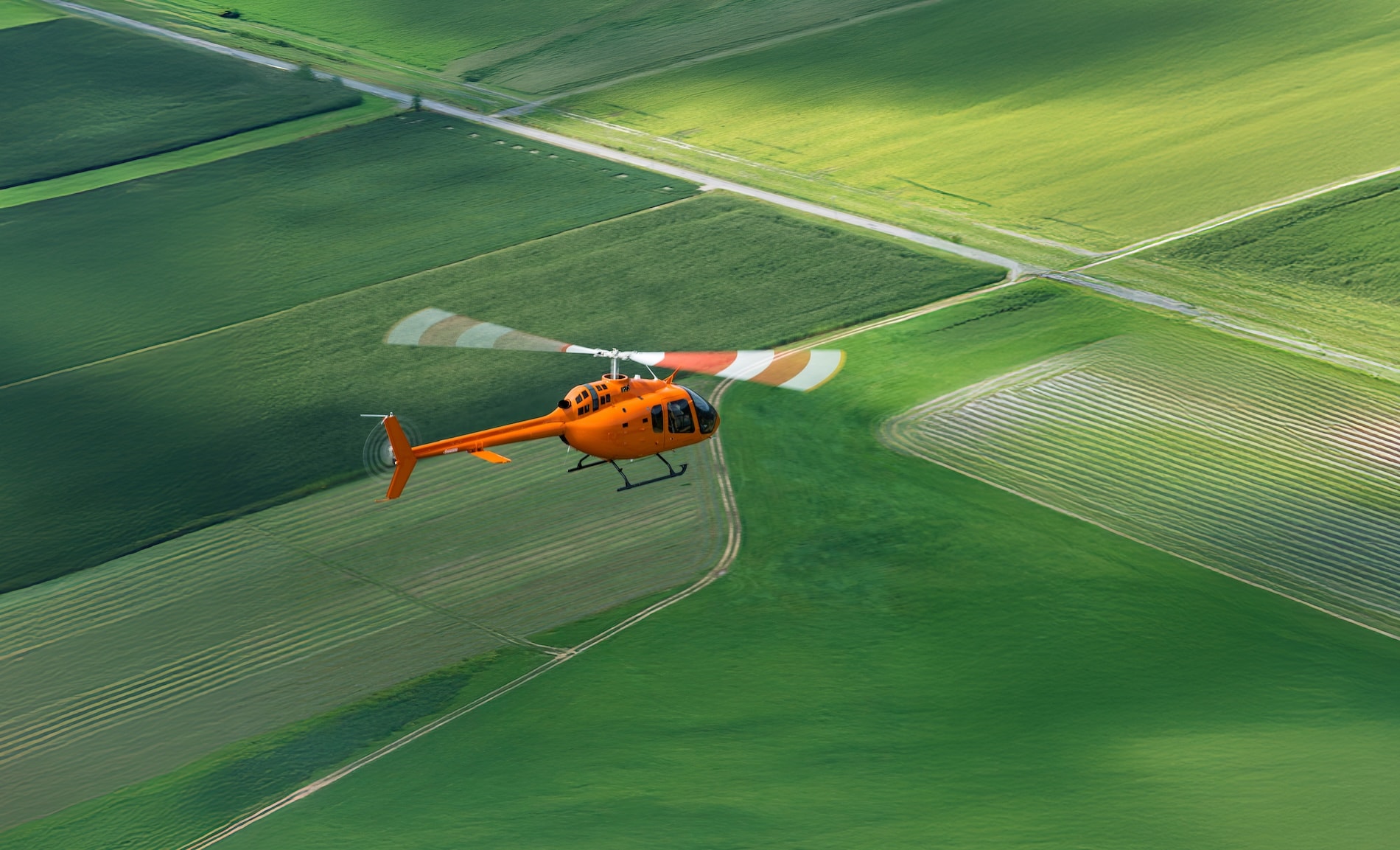 Flight School Next Bell 505 flying over green field