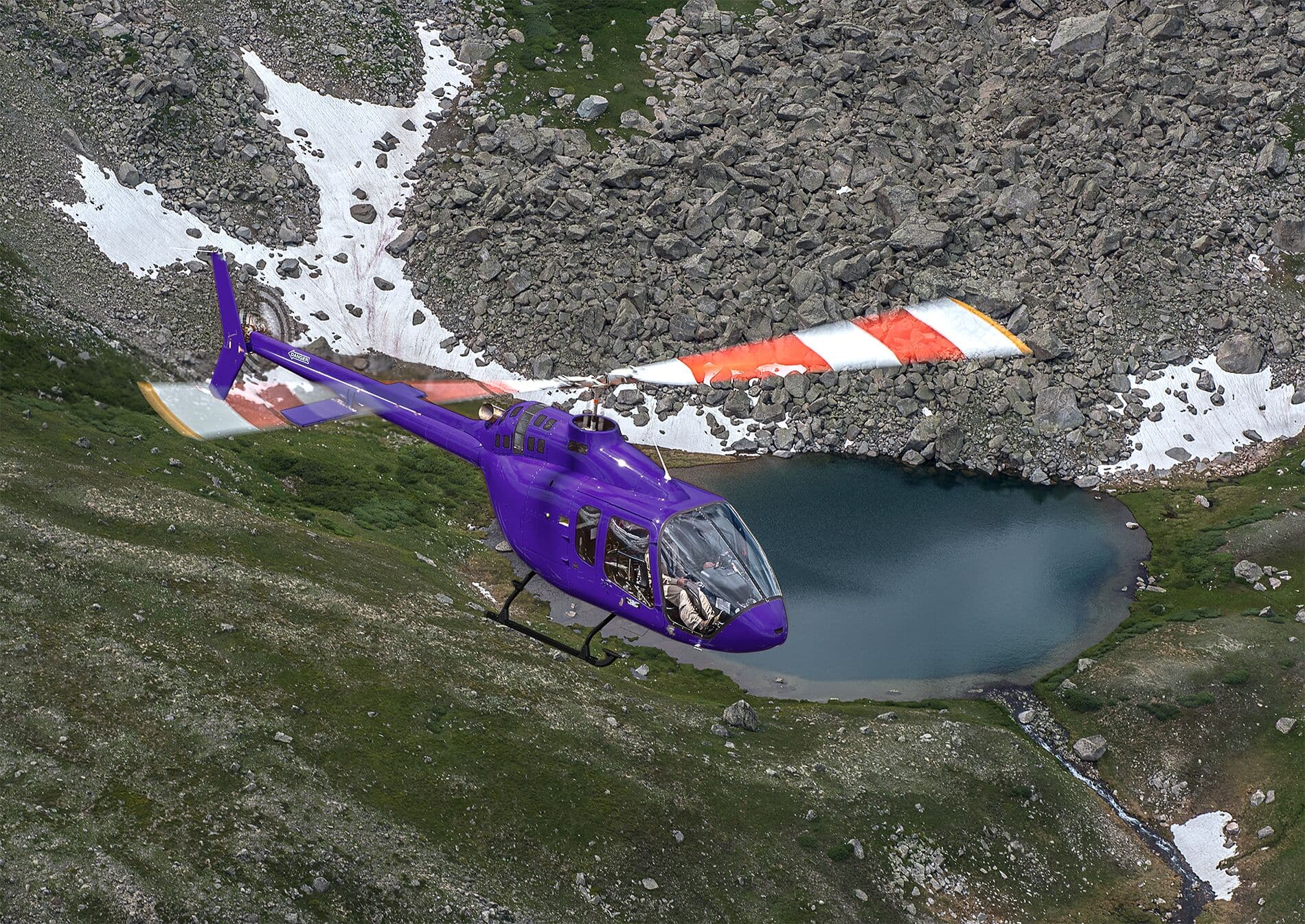 A Purple Bell 505 in flight over the mountains.